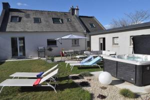 een achtertuin met een hot tub en ligstoelen bij Villa An Castine avec spa pour 6pers proche plages in Saint-Cast-le-Guildo