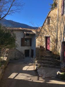 ein altes Steinhaus mit einer roten Tür in der Unterkunft la villa provençale in La Motte-Chalançon