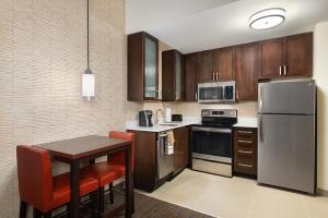 a kitchen with a table and a stainless steel refrigerator at Residence Inn by Marriott Spartanburg Westgate in Spartanburg