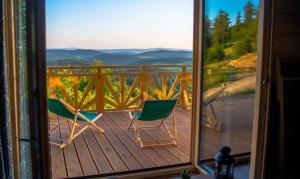 a view from a window of two chairs on a deck at Domek Wilk w Górach Sowich in Jugów