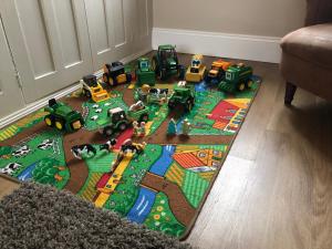 a toy track with toy trucks and tractors on a rug at Moo Cow Cottage Self Catering in Oakham