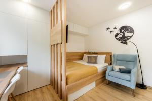 a small bedroom with a bed and a blue chair at Apartments Gros in Radeče