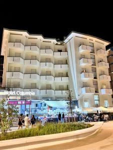 a large building with people walking in front of it at Hotel Columbia Frontemare in Rimini