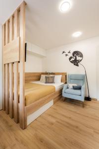 a bedroom with a bed and a blue chair at Apartments Gros in Radeče
