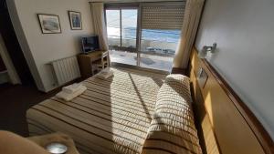 a bedroom with a bed with a view of the ocean at Costanera Hotel in Puerto Madryn