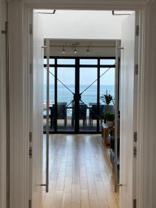 an open door to a room with a view of the ocean at Riviera Apartments - Five Stylish Penthouse Apartments with Unrivalled Sea Views of Teignmouth, Shaldon, The Jurassic Coastline & The Teign Estuary in Teignmouth