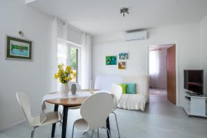 uma sala de jantar branca com uma mesa e cadeiras brancas em Apartment Alex em Labin