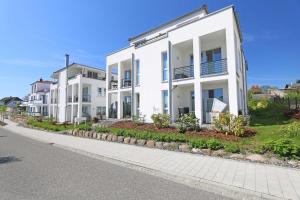 a row of white apartment buildings on a street at Villa Antje - Ferienwohnung 03 in Göhren