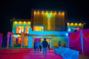 a group of people walking in front of a building with lights at The Nirvana Resort in Chatra