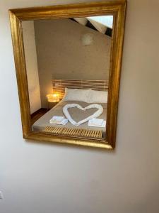 een spiegel die een bed reflecteert met een hartvormige handdoek bij Mini Loft Castello in Thiene