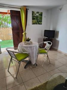 ein Esszimmer mit einem Tisch, Stühlen und einem TV in der Unterkunft Charmant studio à la campagne Sainte-Anne/Gosier en Guadeloupe in Sainte-Anne