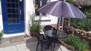 a black table with an umbrella and two chairs at white house in Saint-Germier