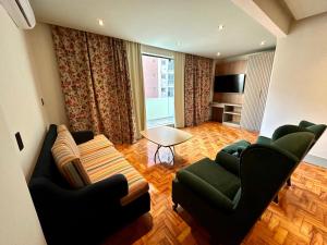a living room with two green chairs and a table at San Michel Hotel in São Paulo