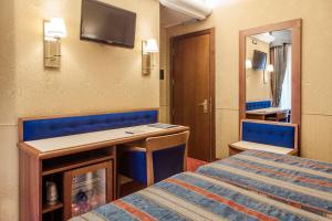 Habitación con cama, escritorio y espejo. en Hotel Des Etrangers en Milán