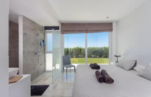 a white bedroom with a large bed and a shower at Villa Dona Julia 2410 Golf and Sea views in Casares