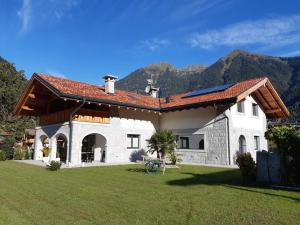 a large white house with mountains in the background at B&B Casa il sasso in Pinzolo