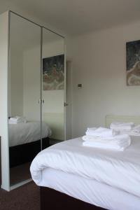een slaapkamer met een wit bed en een spiegel bij Cosy 3 bedroom house in quiet residential area in Manchester