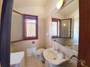 een badkamer met een wastafel, een toilet en een spiegel bij Bilocale n 10 Arbatax vicino al mare in Àrbatax