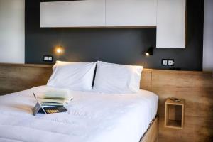 a bed with white sheets and a book on it at Ohai Nazaré Outdoor Resort in Nazaré