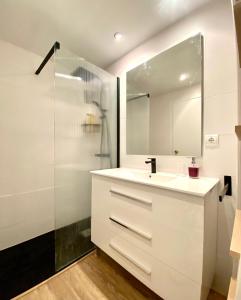 uma casa de banho branca com um lavatório e um chuveiro em Apartamento con 3 habitaciones, terraza y jardin comunitario con piscina en Sant Antoni de Calonge em Sant Antoni de Calonge