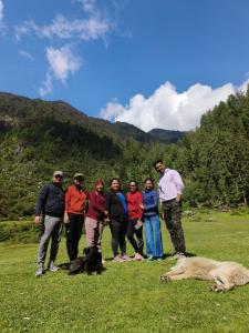 a group of people standing in a field with a dog at Deep In Woods in Jibhi