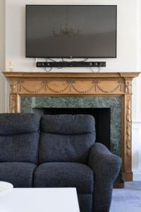 a living room with a couch and a television on a fireplace at Luxury Apartment/Flat Edinburgh City Centre in Edinburgh
