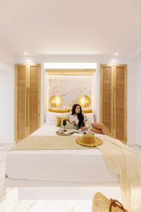 una mujer sentada en una cama grande en un dormitorio en Venus Suite with Hot Tub en Agios Prokopios