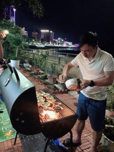 un hombre cocinando comida en una barbacoa en una parrilla en Tít Mít HomeStay en Cao Bằng