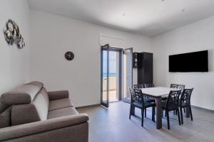 een woonkamer met een bank en een tafel en stoelen bij Residence Medusa by BarbarHouse in Porto Cesareo