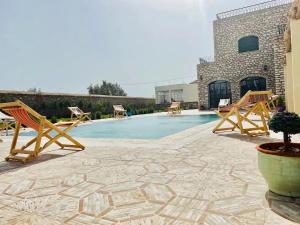 eine Terrasse mit Stühlen und einem Pool in der Unterkunft Unique Villa Castle With Pool in Essaouira