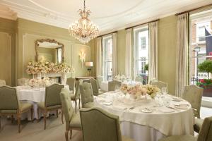 a dining room with tables and chairs and a chandelier at Brown's Hotel, a Rocco Forte Hotel in London