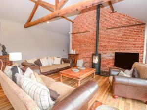 a living room with leather furniture and a brick wall at Shorthorn Barn in Norwich