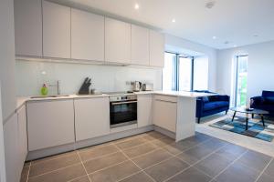 a kitchen with white cabinets and a blue couch at Gorgeous 2 Bedroom Apartment in Manchester in Manchester