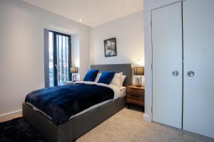 a bedroom with a bed with blue sheets and a window at Gorgeous 2 Bedroom Apartment in Manchester in Manchester