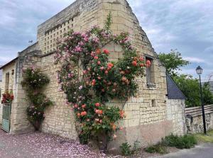 un edificio de ladrillo con flores a un lado. en Le colombier, en Le Coudray-Macouard