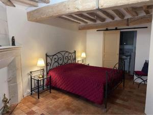 1 dormitorio con cama roja y chimenea en Le colombier, en Le Coudray-Macouard