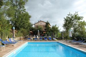a swimming pool with chairs and a table and a house at Agriturismo Ca' Isotta in Castello di Serravalle