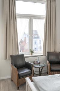 two chairs and a table in a room with a window at Hotel Seehof Norderney OHG in Norderney