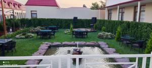eine Terrasse mit einem Teich, Tischen und Stühlen in der Unterkunft Very Well Guest House in Baku