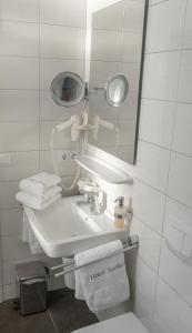 a bathroom with a sink and a mirror and towels at Hotel Seehof Norderney OHG in Norderney