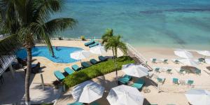 una vista aérea de una playa con piscina, sillas y sombrillas en South Bay Beach Club - Three Bedroom Beachfront Condos by Grand Cayman Villas & Condos, en West Bay