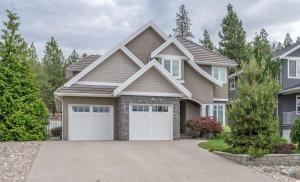 a house with two garage doors in a driveway at Evergreen Condo by Leavetown Vacations in Penticton