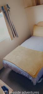 a small bed in a small room with a window at Sunny Seaside chills in Saint Osyth