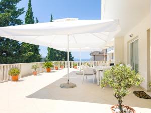 a white umbrella on the patio of a house at Apartments Nikolina in Hvar