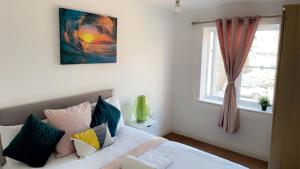 een slaapkamer met een wit bed met kussens en een raam bij Mayfair - Duplex Relocations in Wakefield