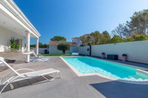 einen Pool mit Stühlen und ein Haus in der Unterkunft Villa de charme in Cabriès