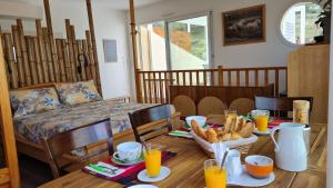 una sala da pranzo con tavolo, pane e succo d'arancia di Chambres d'hôtes B&B La Bergeronnette avec piscine couverte chauffée a Bizanet