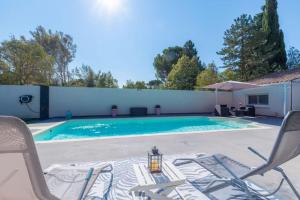 einen Pool mit zwei Gartenstühlen und einem Tisch in der Unterkunft Villa de charme in Cabriès