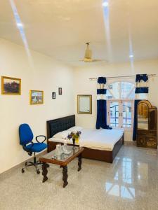ein Schlafzimmer mit einem Bett, einem blauen Stuhl und einem Tisch in der Unterkunft Pall Residency in Srinagar