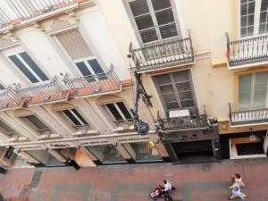 マラガにあるApartamentos Decada Malagaのバルコニー付きの建物、目の前を歩く人々